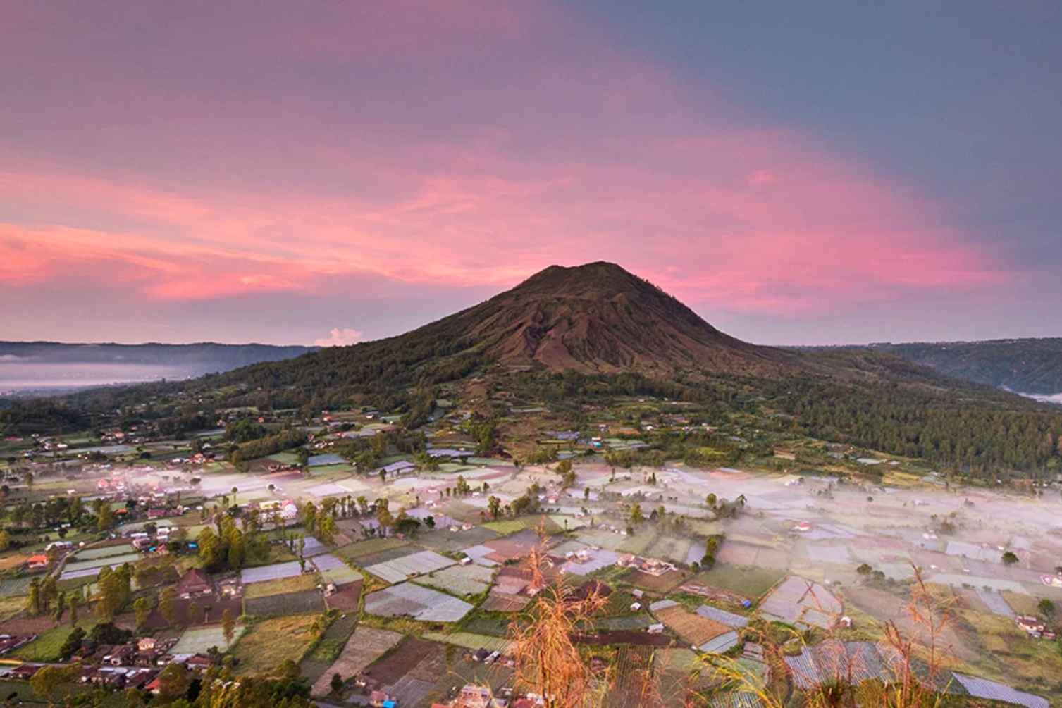 Pemandangan matahari terbit yang memukau di Desa Pinggan dengan latar belakang Gunung Batur yang megah